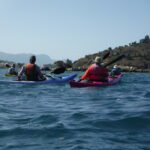 enjoying a day kayaking in Greece. clear blue water, arid lands, and a fine haze in the distance.