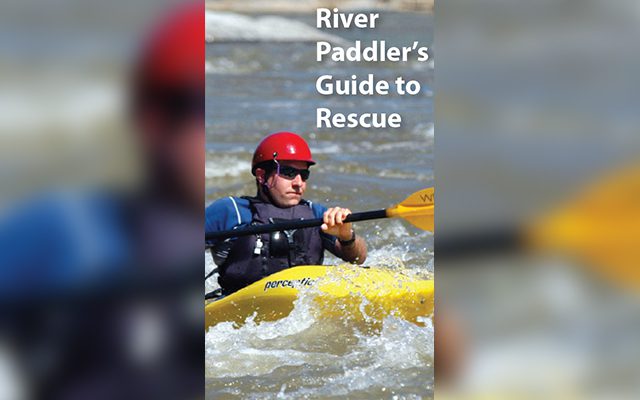 A kayaker wearing a red helmet paddling in whitewater rapids.