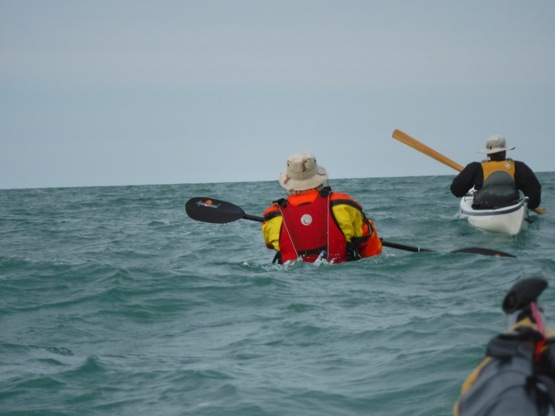 DSCF0210-1 A person kayaking in the ocean wearing a red life jacket and hat.