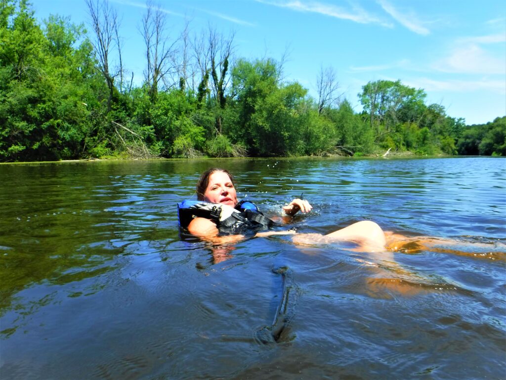 DSCF4385-1024x768 A person relaxing in a calm river surrounded by trees.