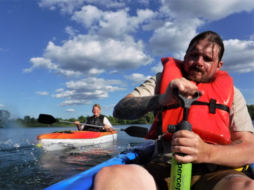 DSCF7481-1024x768 Two men kayaking on a sunny day with blue skies and clouds.