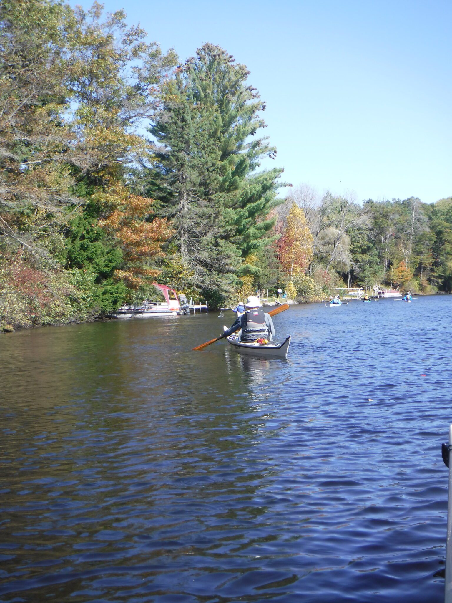 S0010955-1536x2048 Person canoeing on a calm lake surrounded by autumn trees.