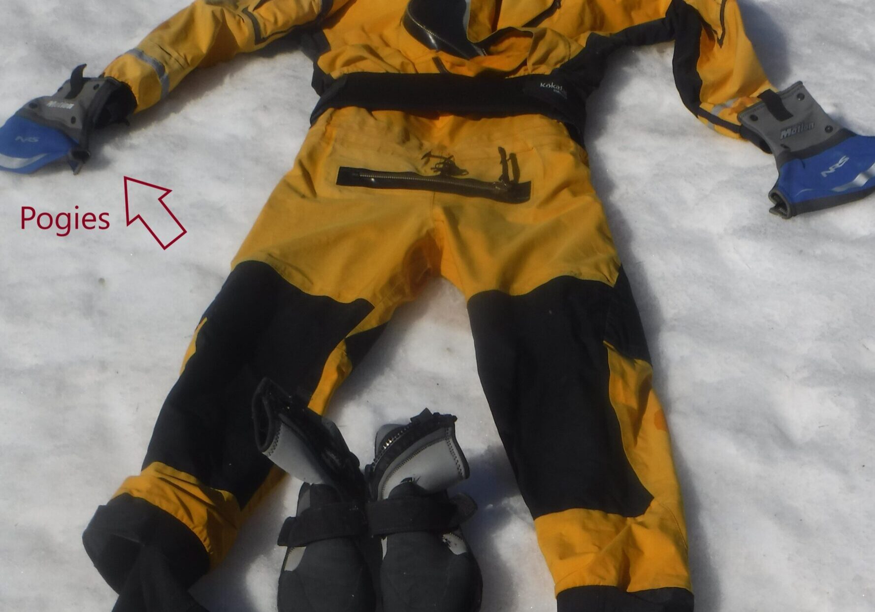 this dry suit is a one piece unit a person wears over the body, only the head and hands are exposed. there are boots and gloves laying next to it.