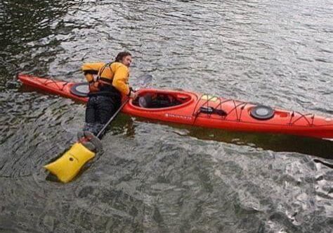 a kayaker who is in the water attempts to get back in with a self rescue on the back deck